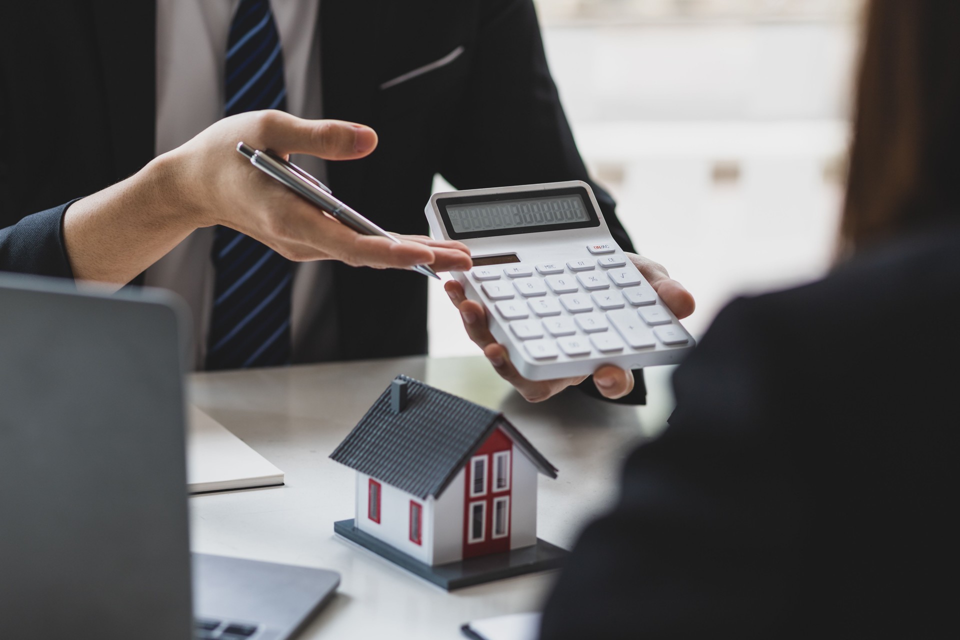 Businessman, real estate agent holding a calculator, presenting a price quote to a client for a house, mortgage, lease, rent, interest, fee, loan, interest.